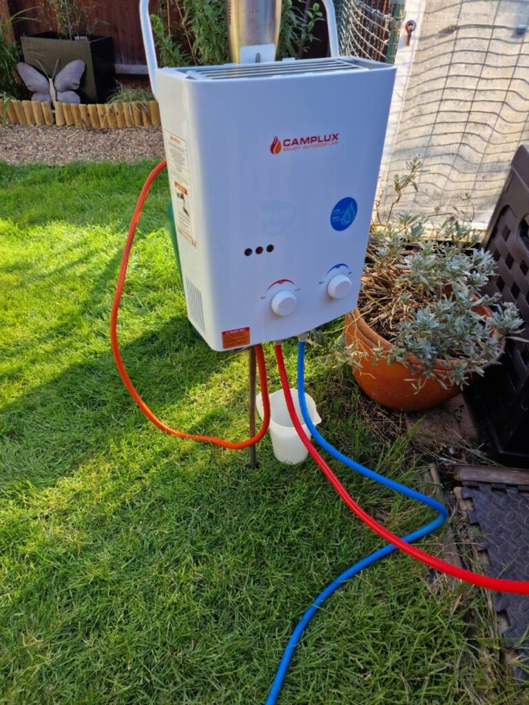 Chauffe-eau à gaz Camplux blanc installé dans un jardin