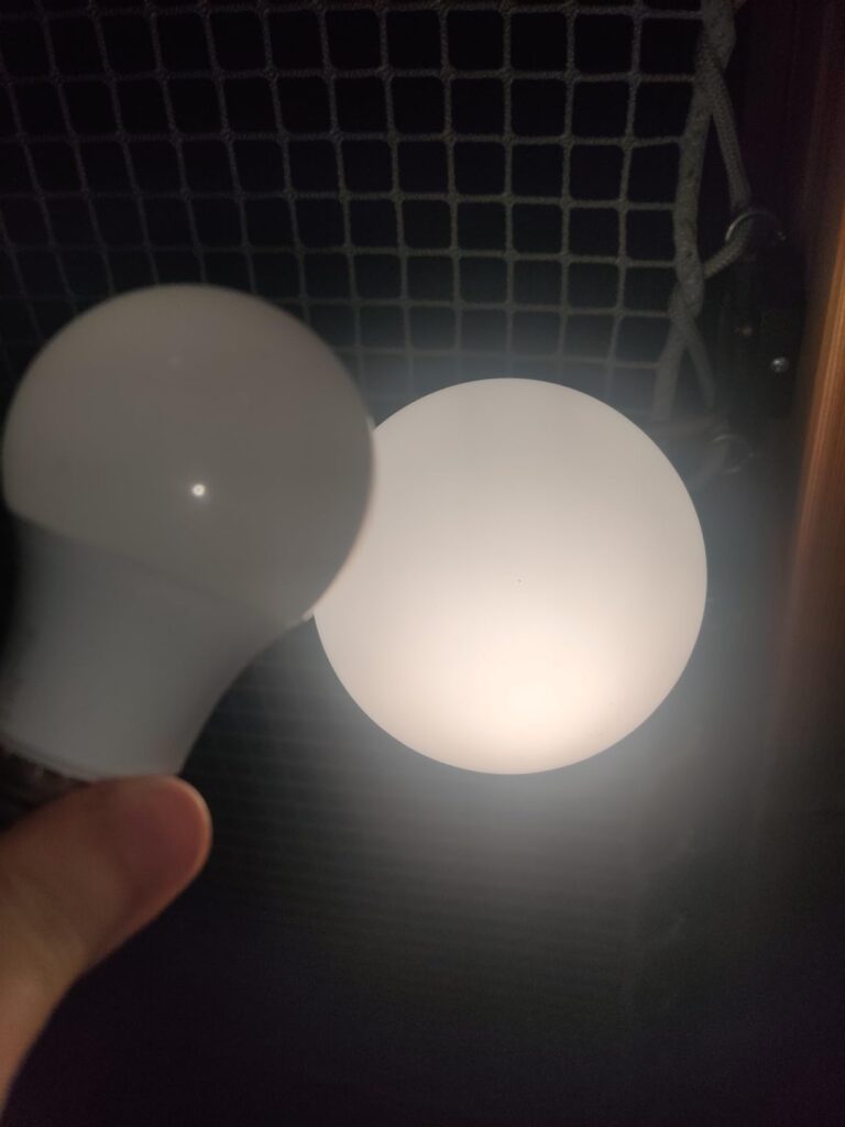 Ampoule LED tenue en main près d'une source lumineuse