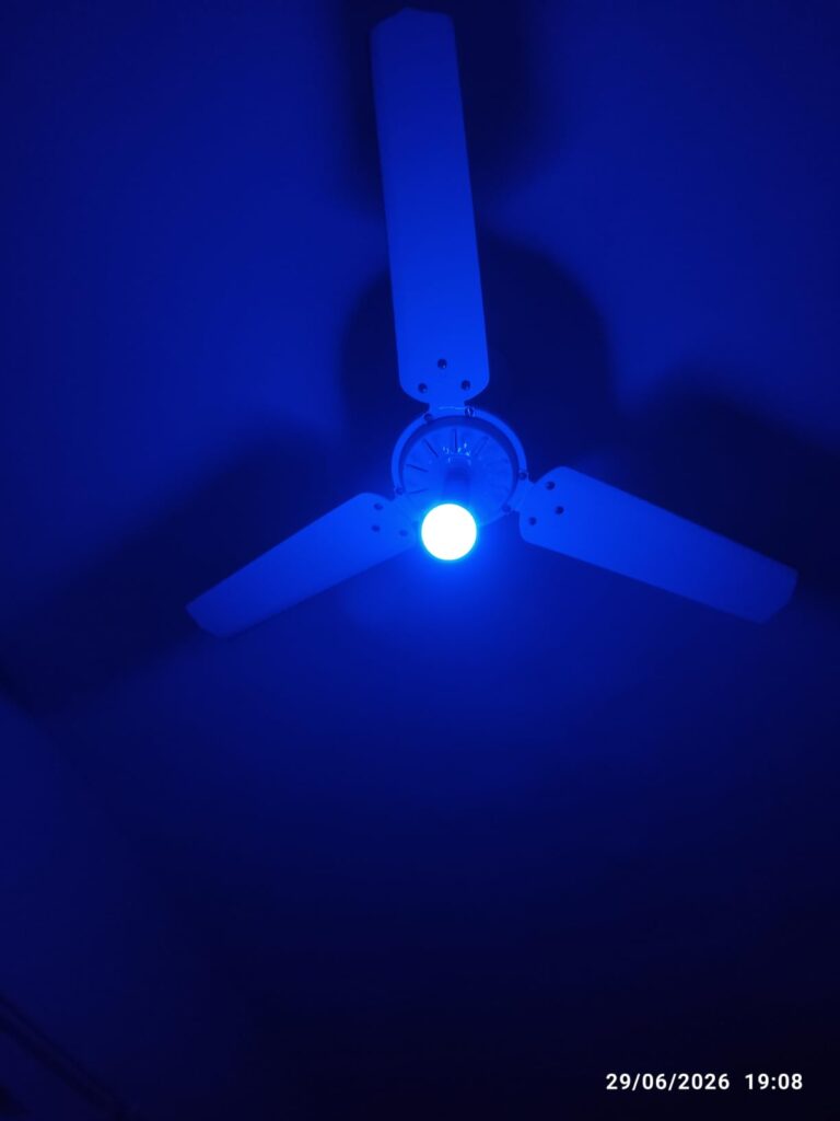 Ampoule allumée en bleu sur un ventilateur de plafond.