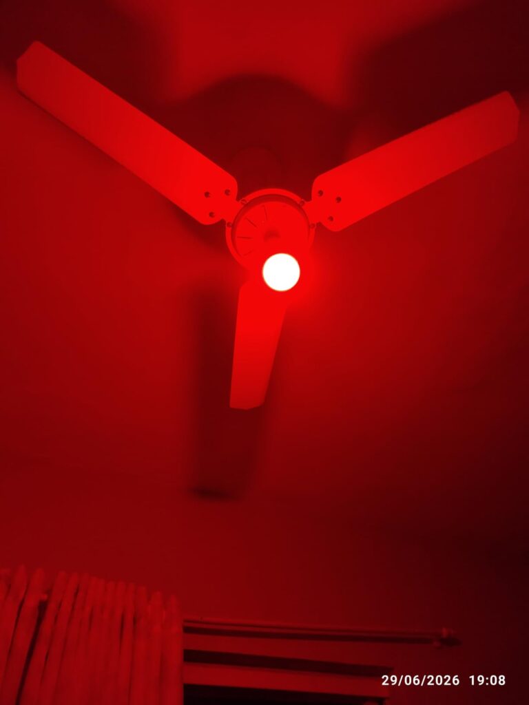 Ampoule allumée en rouge sur un ventilateur de plafond.