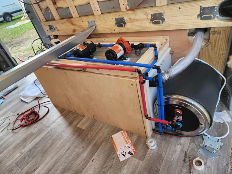 Installation du chauffe-eau noir dans le coffre technique d'un van aménagé