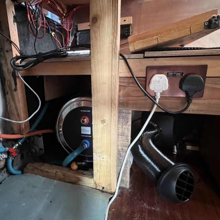 Chauffe-eau installé sous un caisson en bois dans un véhicule aménagé